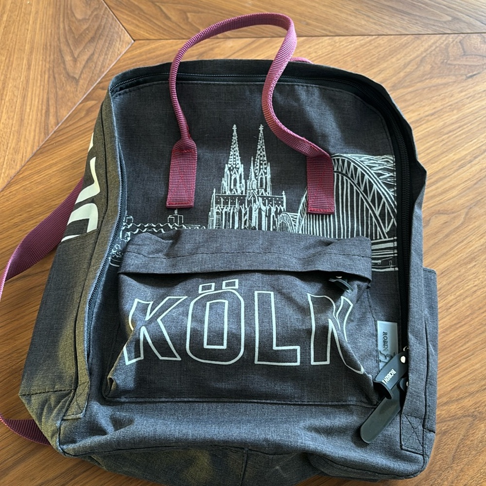 13” backpack dark gray & burgundy with Köln labeled (Cologne, Germany).